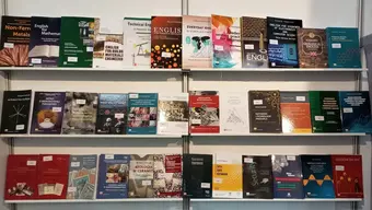 Na zdjęciu trzy półki wystawiennicze, na których prezentują się książki Wydawnictw AGH.