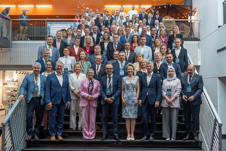 Large group photo of conference attendees standing on a staircase in a modern atrium, posing for a group portrait during the Baltic Rectors’ Forum.