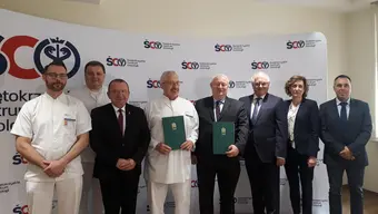 Image of doctors, researchers, and authorities holding folders with the agreement