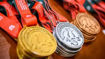 Na zdjęciu ułożone na blacie w stosach złote, srebrne i brązowe medale AMP.