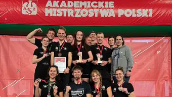 Grupowe zdjęcie sportowców z AGH razem z trenerką. Uśmiechają się, na szyjach mają zawieszone medale.