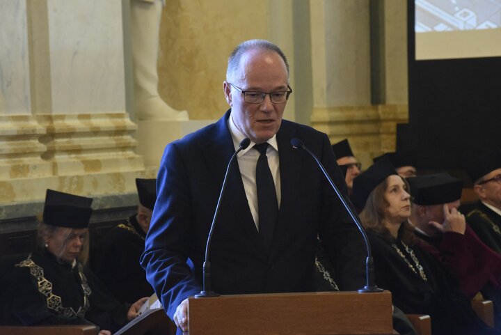 A man wearing glasses giving a speech.