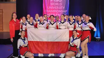 Zespół cheerleaderek reprezentujących Polskę podczas Akademickich Mistrzostw Świata w cheerleadingu prezentuje zdobyte srebrne medale i flagę Polski.