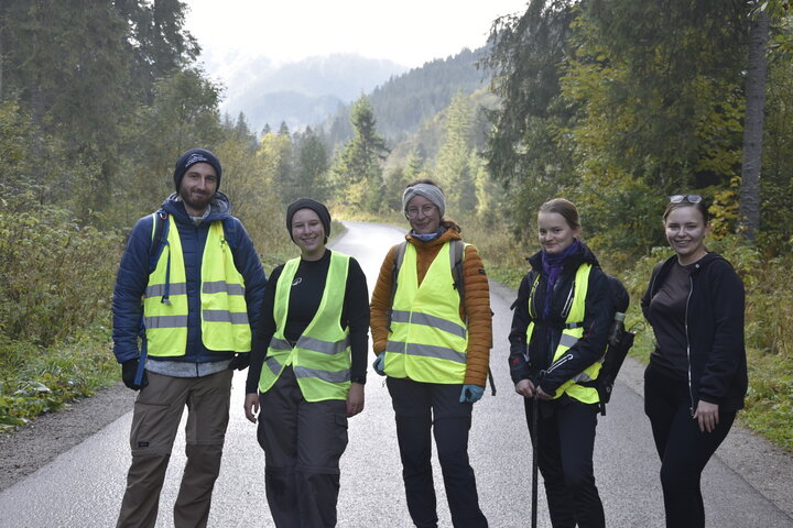 A group of young people in high-visibility vests on a mountain trail.