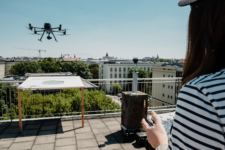 A female drone operator controlling a drone flight above the rooftop landing area..