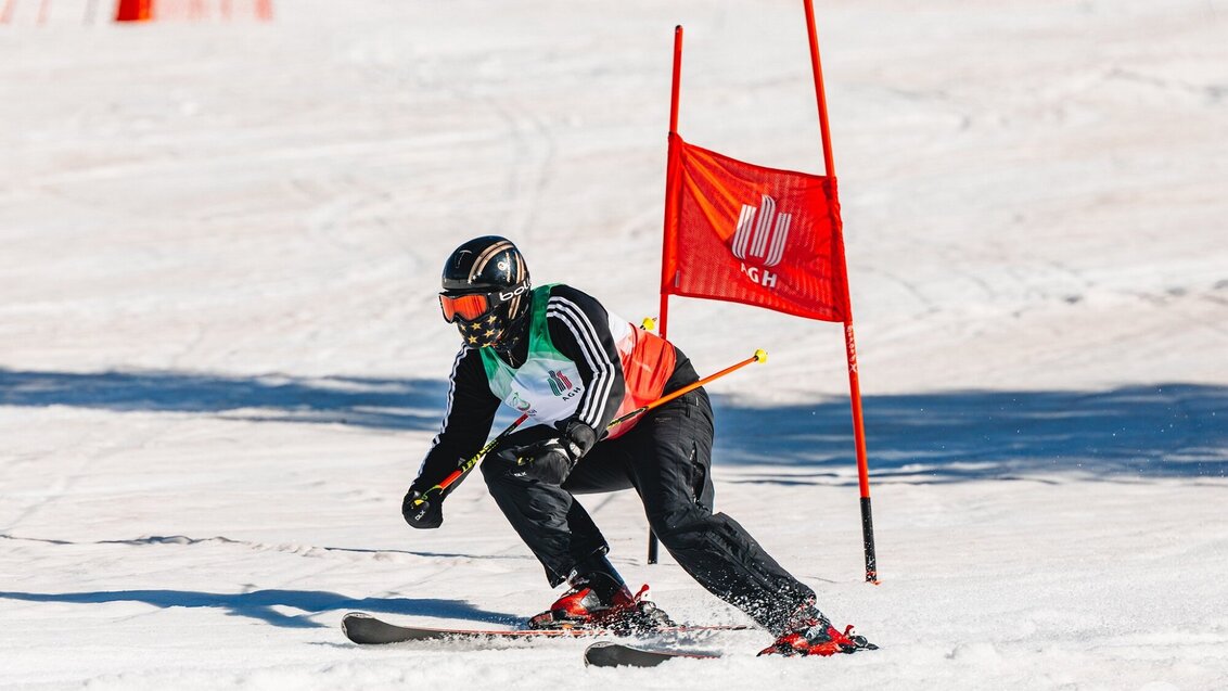 A ski competitor going down a slope in a sports uniform, helmet, and goggles.