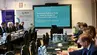 Uczestnicy posiedzenia siedzą w sali konferencyjnej. Widoczny ekran z prezentacją.