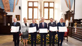 The photo shows the signers of the letter, six people in a row holding copies of the document and presenting them to the camera.
