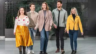 Na zdjęciu młodzi ludzie (dwóch mężczyzn, dwie kobiety), idą obok siebie korytarzem, są radośni.