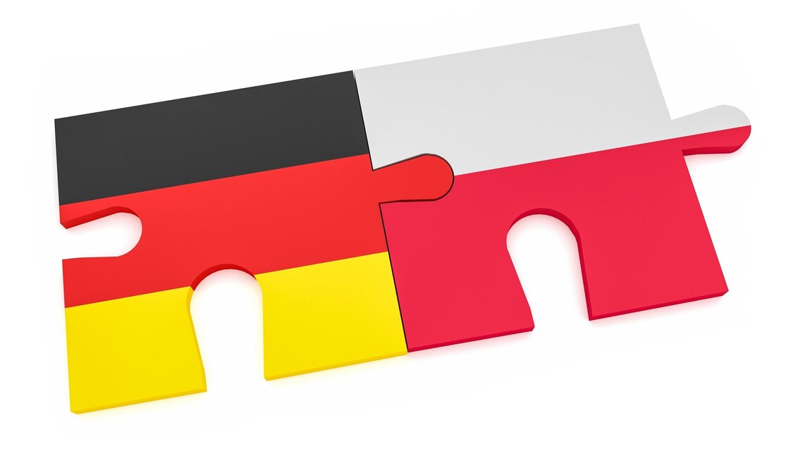 Grafika. Na białym tle dwa dopasowane do siebie puzzle: jeden w kolorach flagi niemieckiej, drugi w kolorach flagi polskiej.