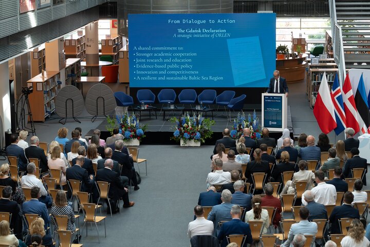 Wide view of a formal conference in a large atrium.