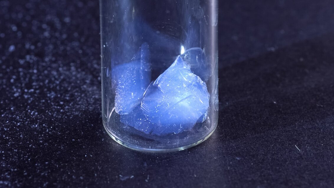 A blue aerogel in a glass container.