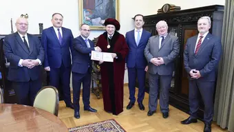 Image of authorities of two universities, the AGH University Rector portrayed holding a diploma and shaking hands with the other party