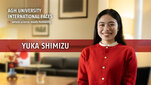 A banner of an episode in the AGH University International Faces series featuring an image of a young woman in a red cardigan seated at a table.