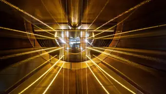 The inside of the Large Hadron Collider that resembles a wide gold tunnel. It looks as if beams of light are travelling through the tunnel.