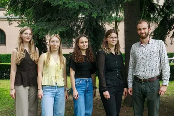 Grupa czterech kobiet i jeden mężczyzna stoi na tle zieleni w parku