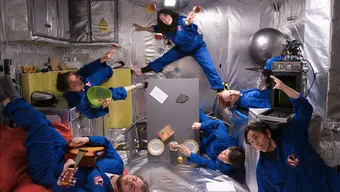 Na zdjęciu habitat misji kosmicznych: sześcioro osób ubranych w jednakowe granatowe kombinezony lewituje w pomieszczeniu urządzonym na wzór tych, jakie znajdują się na statku kosmicznym.