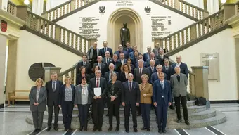 Grupowe zdjęcie uczestników zebrania plenarnego Komitetu wykonane na schodach w holu reprezentacyjnym budynku głównego AGH.