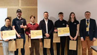 Photo of the winners of the competition holding paper gift bags and yellow diplomas