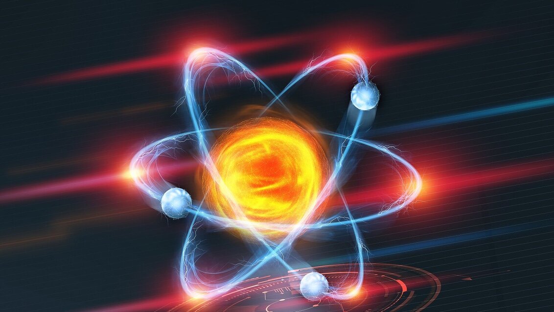 Kolorowa grafika 3D przedstawiająca jądro atomu, wokół którego po elipsach wirują elektrony.