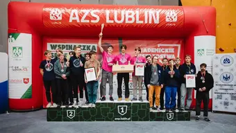 Zdjęcie medalistów zawodów na podium - trzy męskie drużyny stoją na podium, na miejscach, które zajęły w zawodach. Na szyjach zawodników wiszą medale. Reprezentanci każdej z drużyn trzyma w dłoniach pamiątkowy puchar.