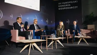 Four people during a panel discussion. The man on the left holds a microhpone.