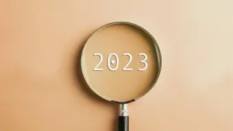 Grafika ilustracyjna przedstawiająca lupę, której soczewka skierowana jest na napis "2023".
