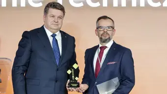 Image of two vice-rectors in official setting holding an award on stage