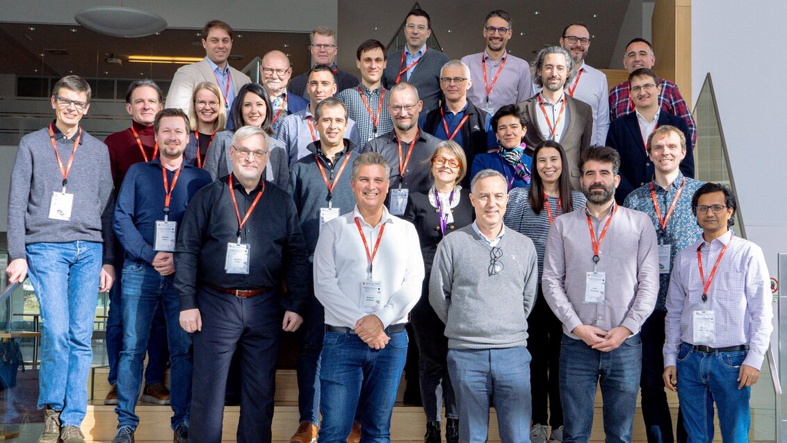 Image of a large group of people standing on stairs, wearing orange lanyards