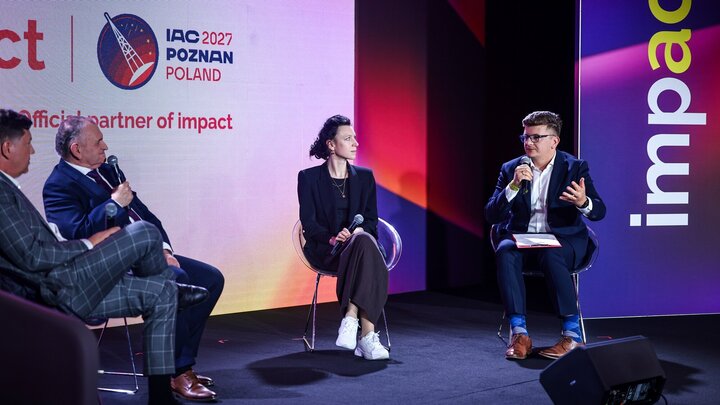 Four speakers sitting and talking on stage. 