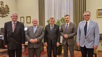 Image of 5 men - university autorities and the Minister of Science standing in a room with a Polish emblem on a wall