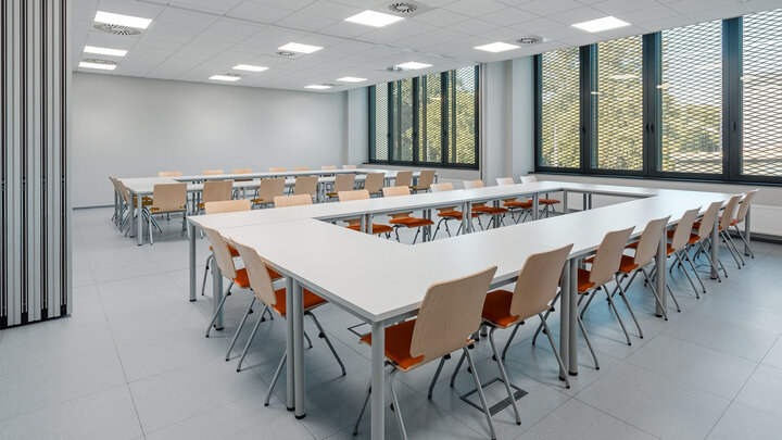 Zdjęcie sali spotkań w SCK. Duża, przestronna sala, pośrodku niej dwa stoły konferencyjne i krzesła. Przy jednym stole może zasiąść kilkanaście osób.