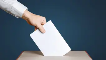 Zdjęcie ilustracyjne: ręka wrzucająca do urny głos wyborczy