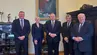 Grupa pięciu eleganckich osób stoi w gabinecie