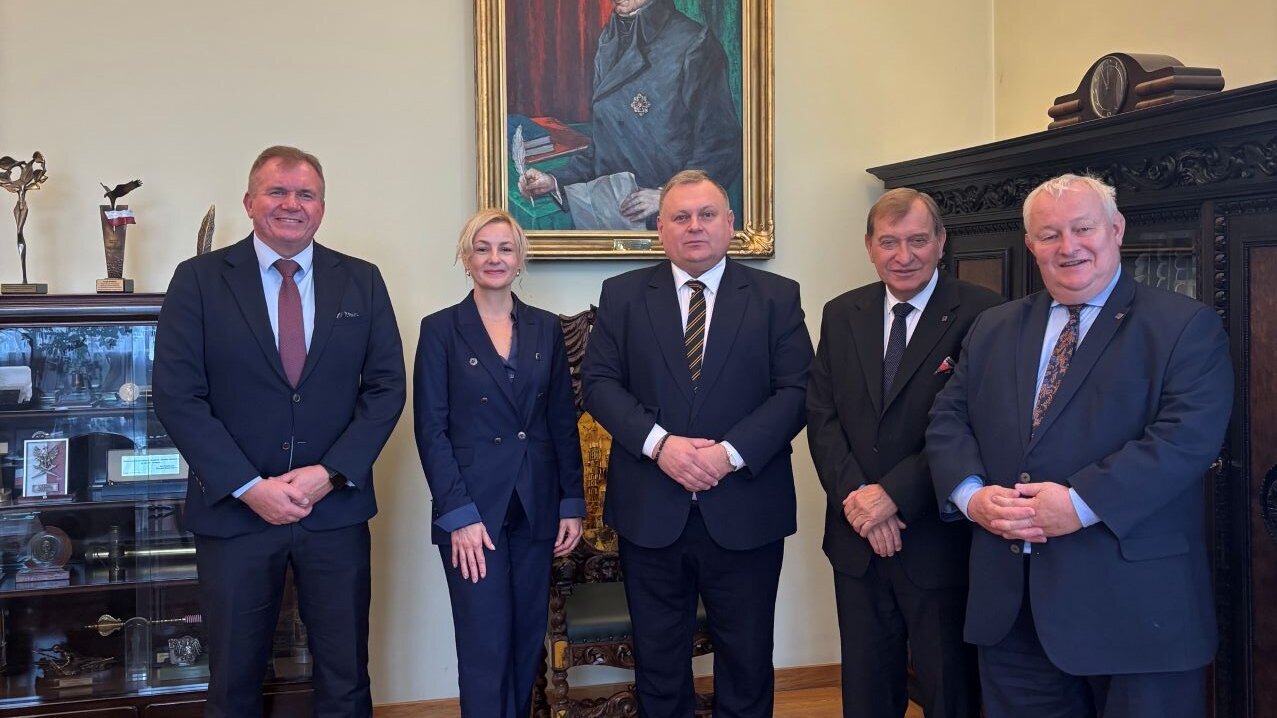 Grupa pięciu eleganckich osób stoi w gabinecie