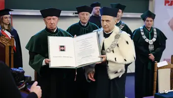 Uroczysta ceremonia w auli. Rektor PŚk oraz prof. Dziech w togach ceremonialnych prezentują otwarty dyplom z herbem uczelni.