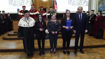 A photograph of the medallists standing in front of the podium with the rector and vice voivode in the AGH University assembly hall.