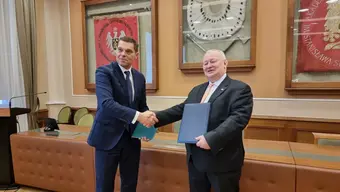 Image of Professor Wiśniowski shaking hands with the president of AQUA, both of them are holding folders of respective entities.