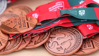 Zdjęcie brązowych medali AZS nawleczonych na szarfy i leżących na stole.
