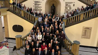 Grupowe zdjęcie osób uczestniczących w wydarzeniu inauguracyjnym. Kilkadziesiąt osób stoi na schodach w holu głównego budynku AGH, pozując do zdjęcia.