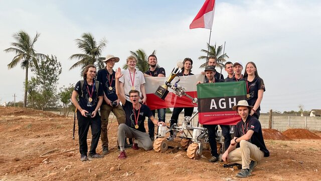Na zdjęciu zwycięska drużyna AGH Space Systems wraz z łazikiem Kalmanem. Studenci trzymają flagę Polski oraz AGH