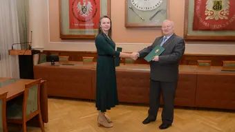 Na zdjęciu sygnatariusze umowy tuż po jej podpisaniu podają sobie dłoń. Zdjęcie wykonane w sali konferencyjnej.