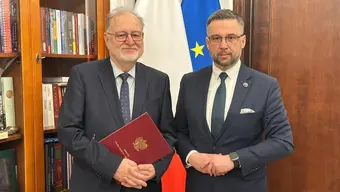 Professor Kąkol with Minister Kulasek posing for a photo in an office setting. Professor Kąkol is holding a burgundy folder with the Polish eagle.