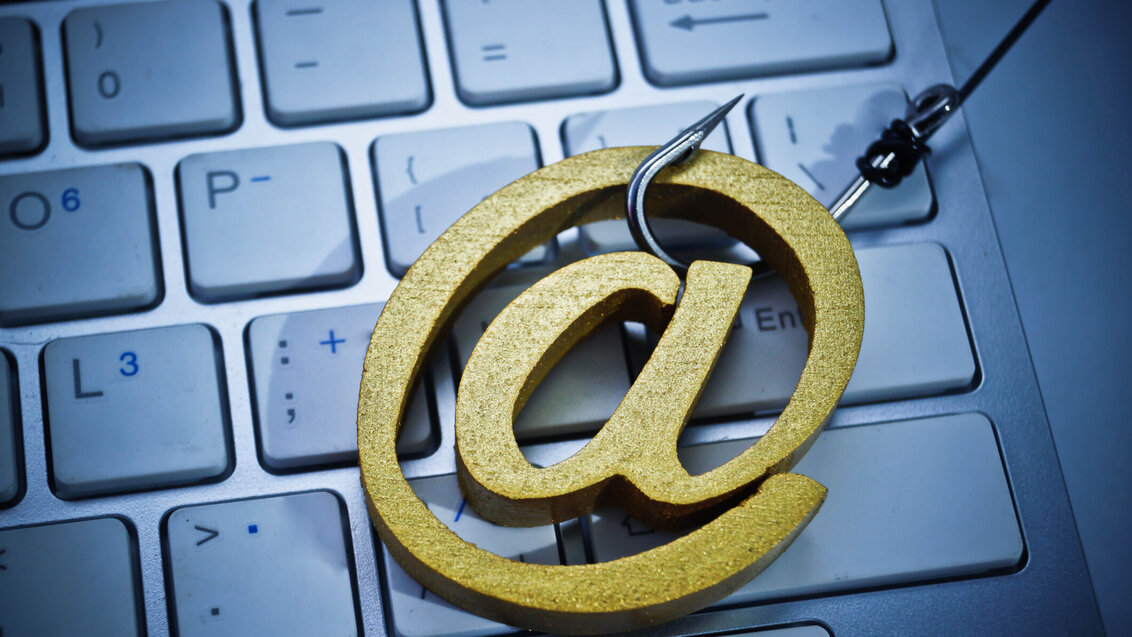 Image of the email symbol 'at' on a hook on a white keyboard