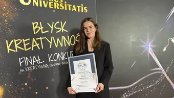 Osoba na zdjęciu trzyma w rękach pamiątkowy dyplom. W tle widać ściankę z kolorową grafiką i napisami "Genius Universitatis", "Błysk kreatywności" oraz "Finał konkursu na kreatywną kampanię szkoły wyższej".