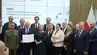 Grupowe zdjęcie sygnatariuszy porozumienia. Jedna z osób prezentuje podpisany dokument.