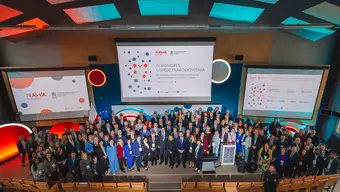 Grupowe zdjęcie uczestników i uczestniczek kongresu - stoja obok siebie na dużym podium, za nimi ekrany ze slajdami.
