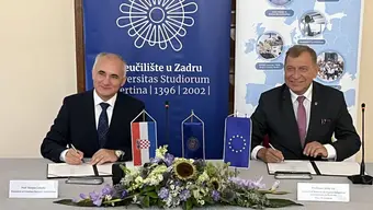 Za stołem prezydialnym siedzą ubrani w garnitury Rektor AGH Jerzy Lis i Przewodniczący Konferencji Rektorów Chorwackich. Panowie są w trakcie podpisywania porozumienia.