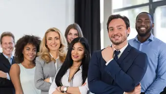 Na zdjęciu grupa młodych, uśmiechniętych osób, ubranych w stylu biznesowym.