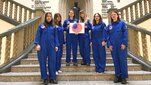 Mission participants dressed in blue astronaut uniforms. The photo was taken in the hall of the Main Building on a large staircase.